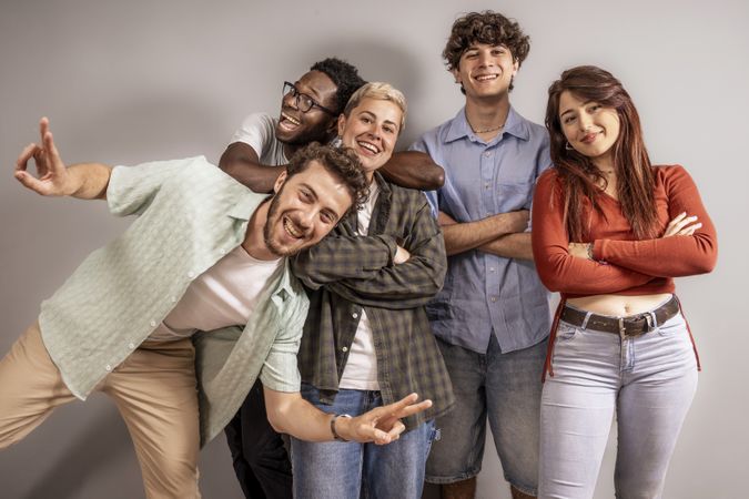 Five multicultural friends posing together in casual studio portrait laughing and having fun