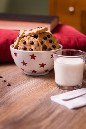 Chocolate chip cookies and milk on wood background