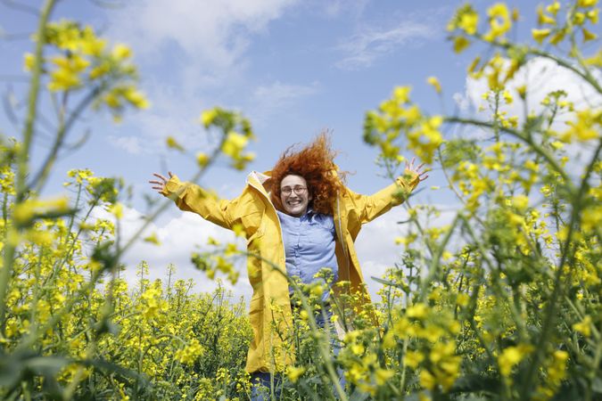 Joyful red haired woman smiling in a rapeseed field