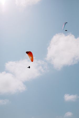 Faceless people paragliding in blue sky
