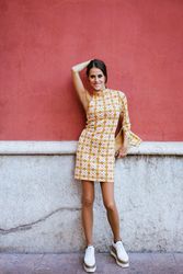 Happy woman in trendy outfit standing by red wall in daylight