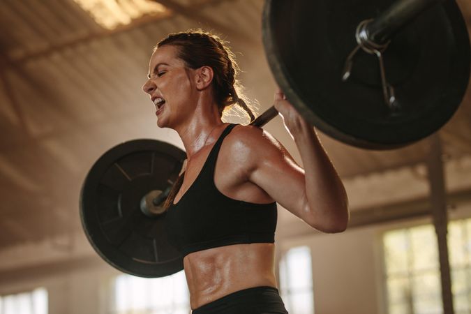 Female putting in effort while exercising with heavy weights
