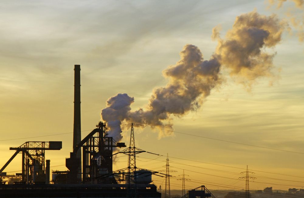 Industrial site with smoke clouds during sunset