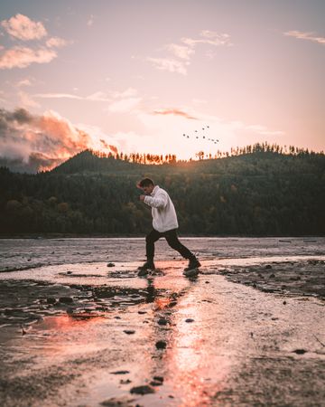 Man in walking beside mountain during sunset