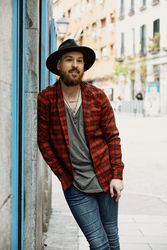 man standing leaning on wall and smiling