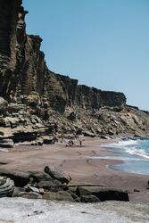 People under rugged cliffs in Lanzarote