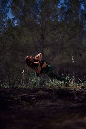 Woman doing Parivritta Utkatasana posture in forest