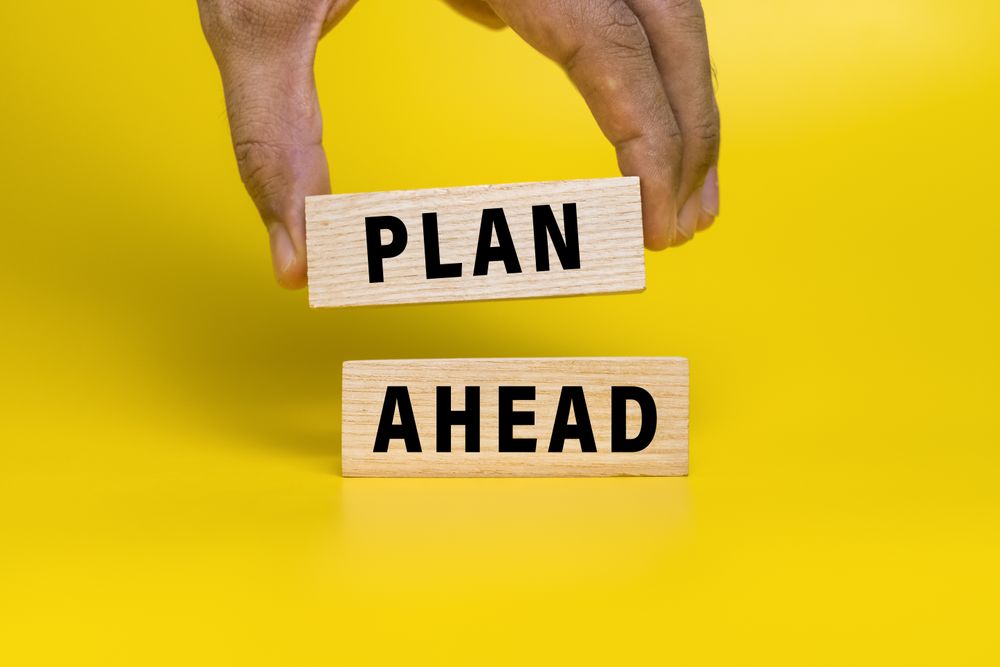 male hand put wooden blocks with plan ahead words isolated on yellow background
