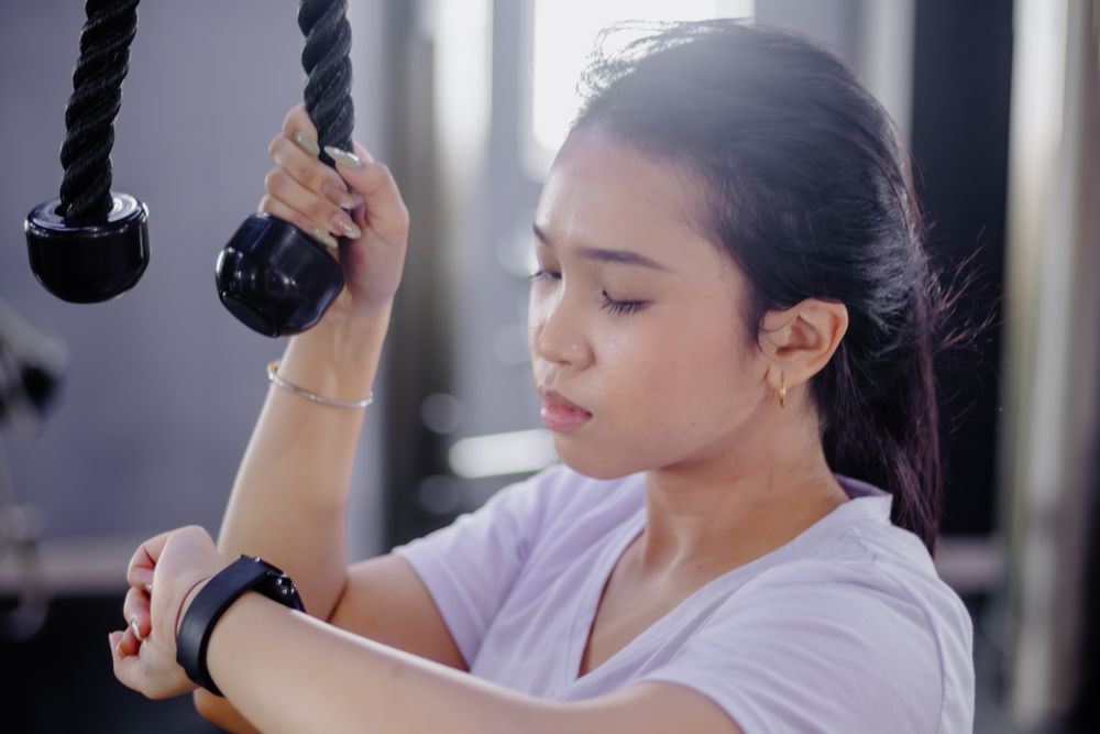 Focused Asian Woman Checking Progress on Smartwatch at the Gym