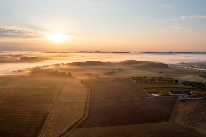 Aerial view with rural scenery at sunrise with foggy agricultural fields