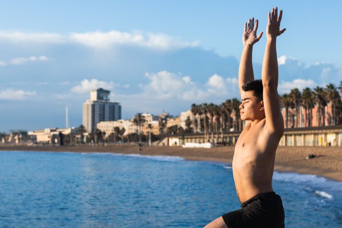 Asian man doing yoga pose on seashore