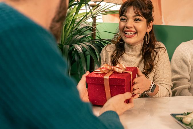 Happy woman receiving a surprise gift from a man during a celebration