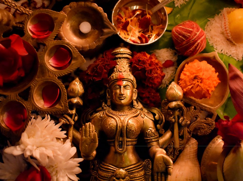 Buddha golden statue surrounded by diya and flowers