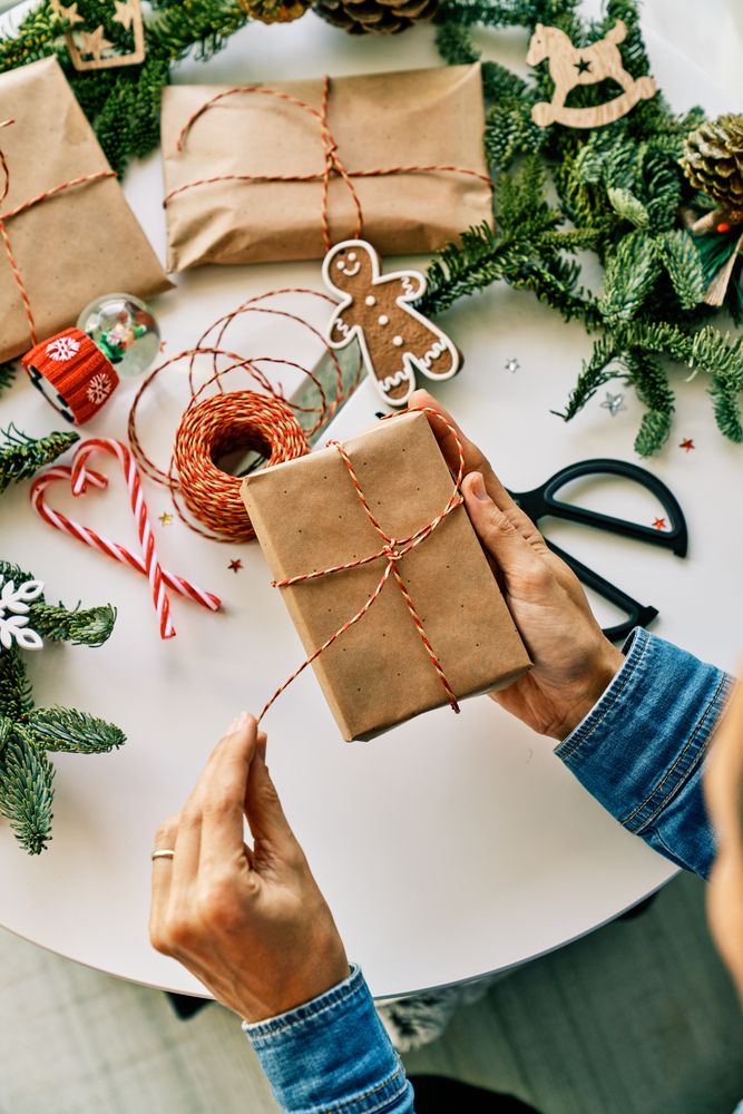 Crop person opening Christmas gift box above table