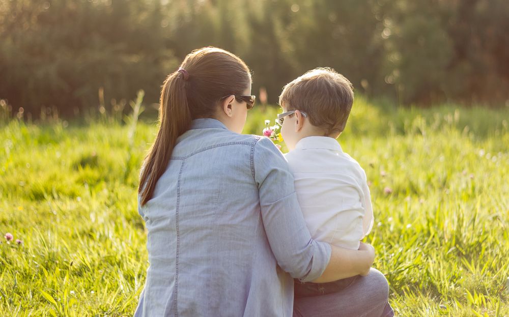 Son giving bouquet of flowers to mother in field
