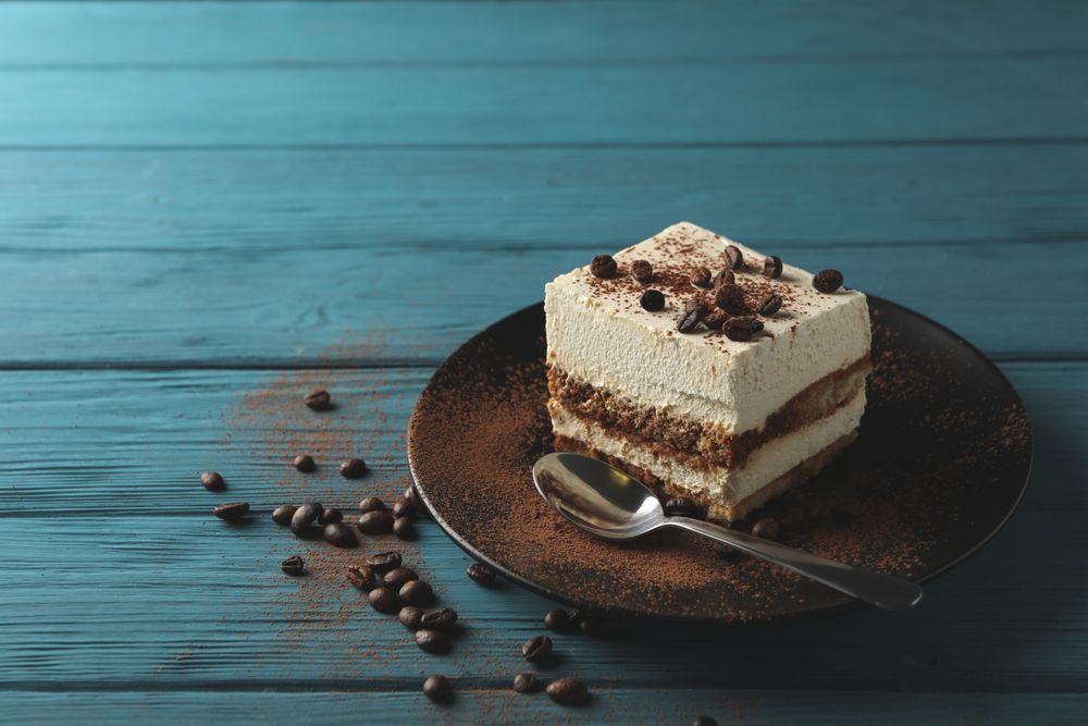 Plate with tasty tiramisu on wooden background, space for text