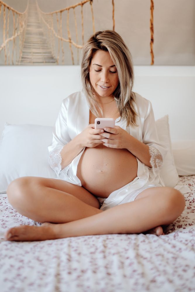 Smiling pregnant woman using smartphone at home