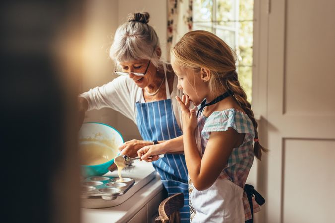 Grandmother teaching grandchild how to bake cupcakes