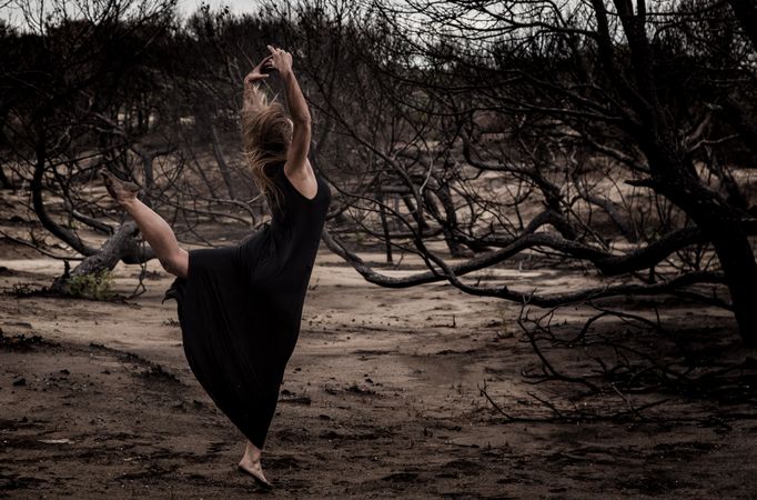 Woman dancing between dry trees