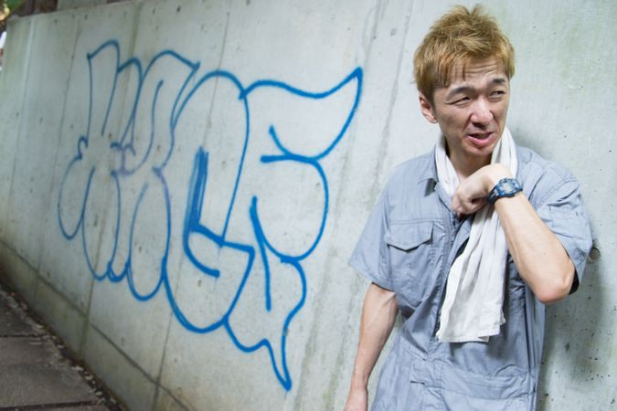 Exhausted man in work suit leaning on graffiti wall