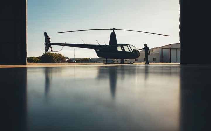 Silhouette of helicopter in the hangar with a pilot