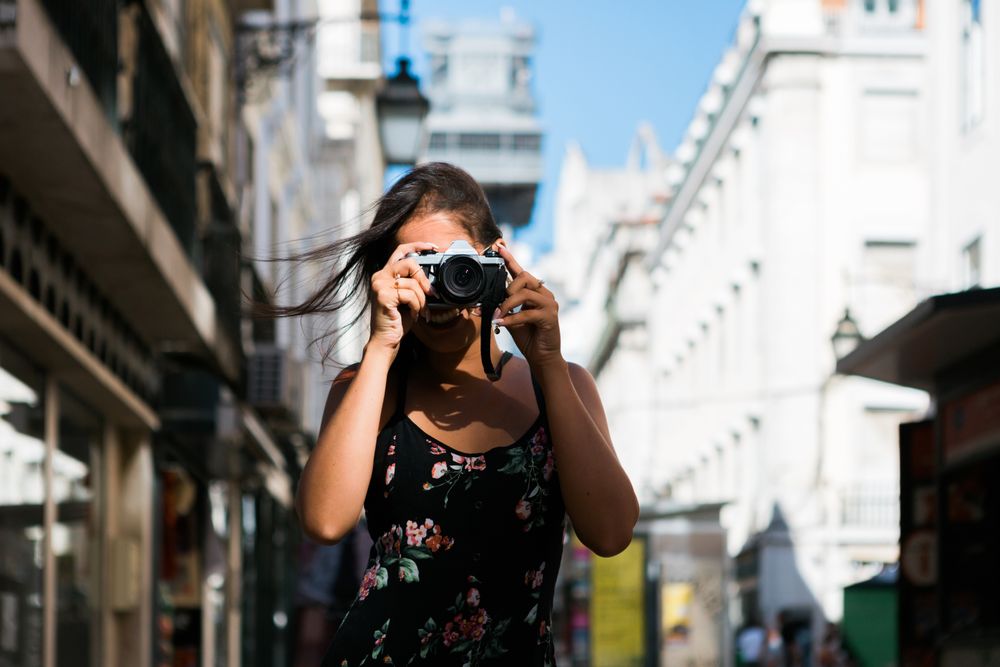 Casual woman taking photo with camera while standing on street