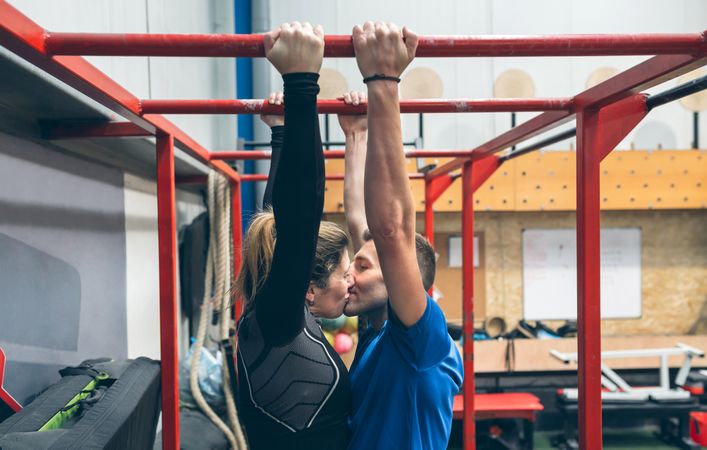 Athletes kissing exercising on monkey bars