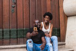 Black positive couple taking selfie together on cellphone