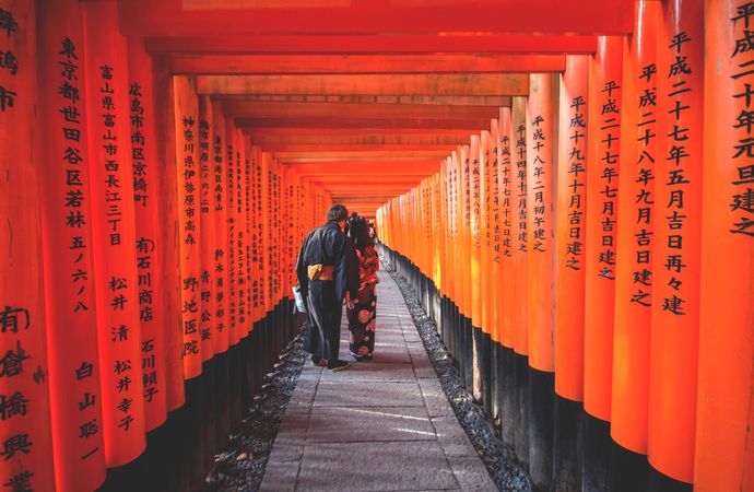 Back view of man and woman in kimonos walking in Thousand Torii Gate in Kyoto, Japan