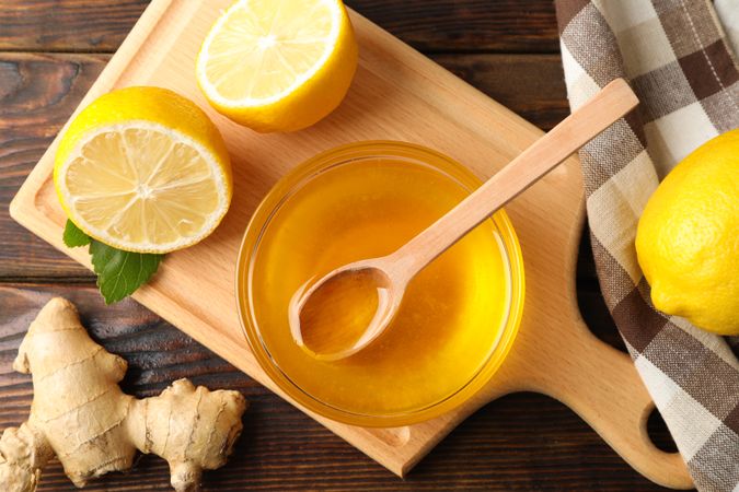 Honey, ginger, lemons and towel on wooden background, top view