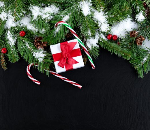 Top Border of Snowy evergreen tree branches with gifts on stone background