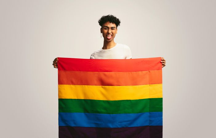 Man sticking out tongue and winking holding pride flag