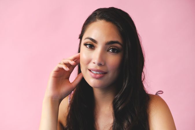 Wistful Hispanic woman looking at camera in pink room