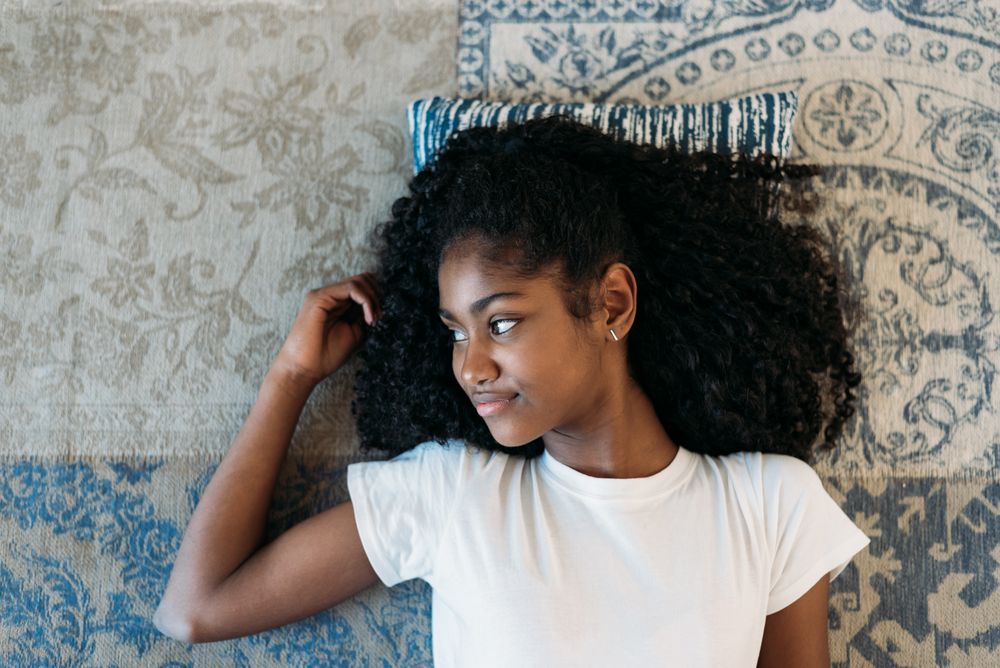 Beautiful young Black teenage girl lying down in a rug