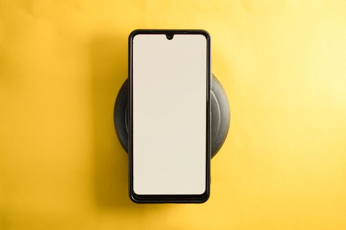 Mock up phone on circular accessory on yellow table