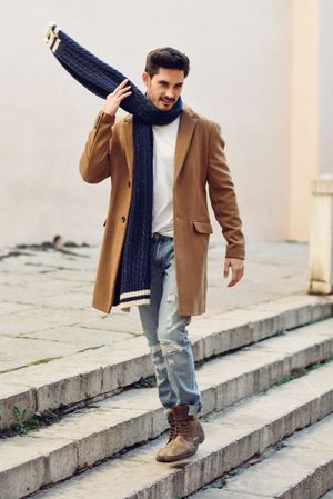 Man wearing winter clothes in the street adjusting scarf