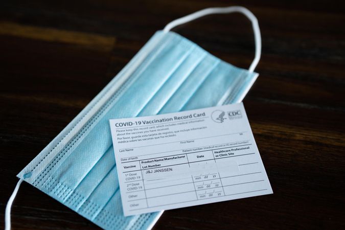 Vaccination card and PPE mask on table