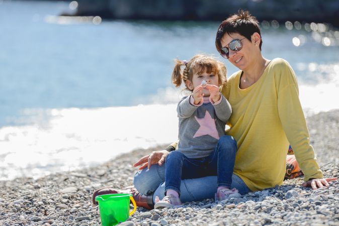 Short haired woman and little girl collecting rocks on a beach