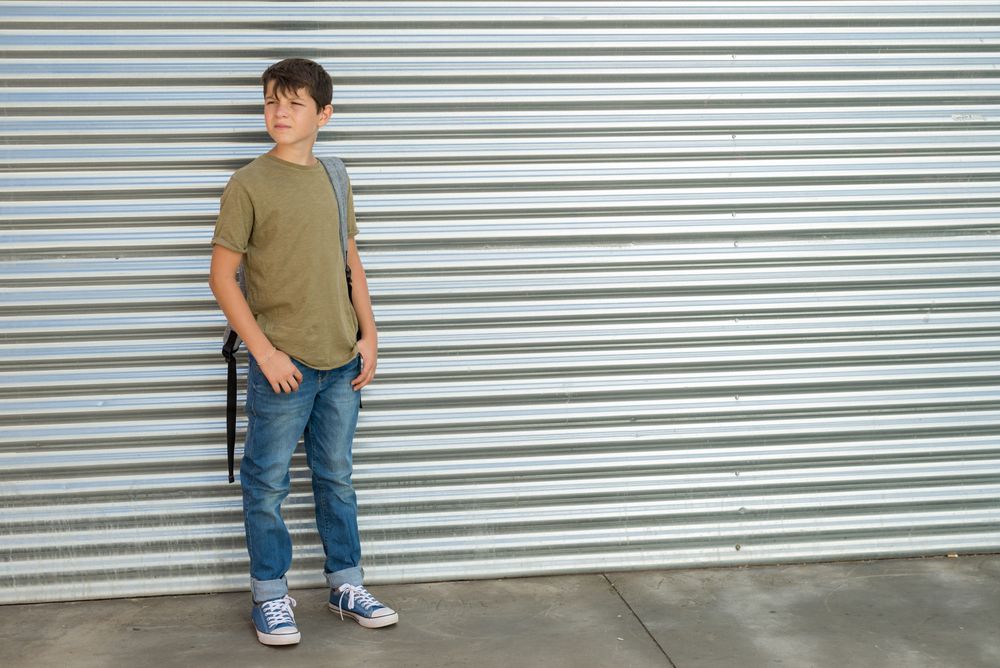 Teenager boy in back pack standing outside of street shutter