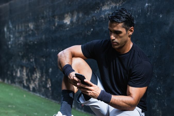 Focused fit man browsing smartphone during training