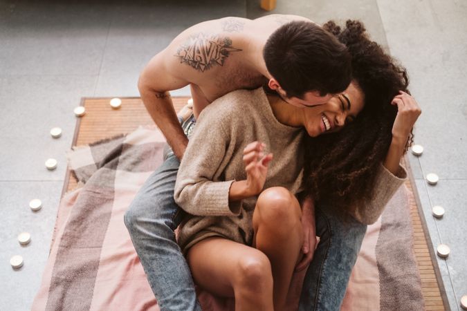 Multiethnic couple hugging on floor at home