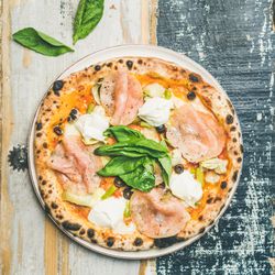 Freshly made wood fire oven pizza with spinach, ham and olives, square crop