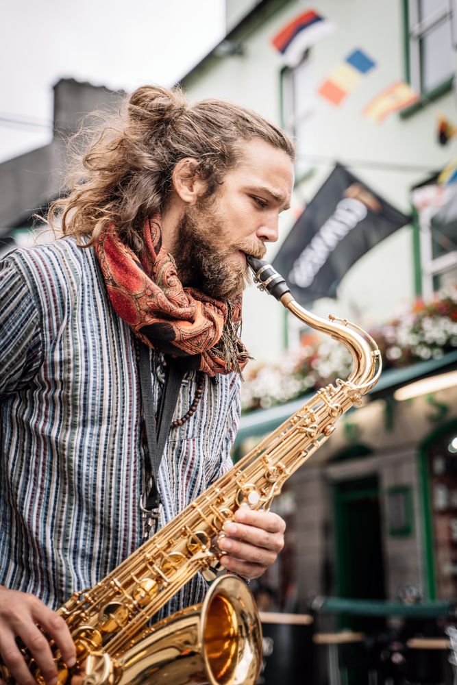 Male saxophonist plays sax in the street