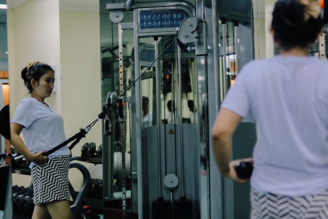 young woman in a gym actively exercising using a cable machine