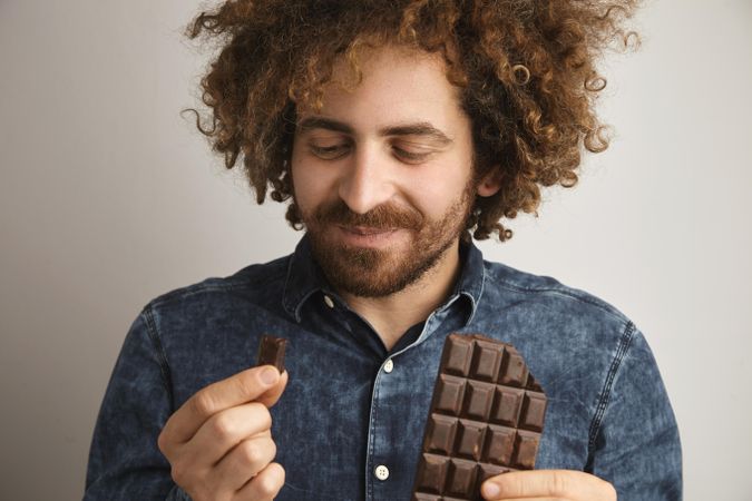 Man holding a bar of chocolate with a piece broken off