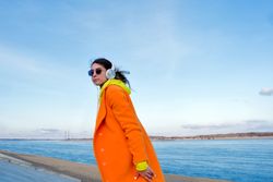 Woman listens to music with headphones while walking on coast