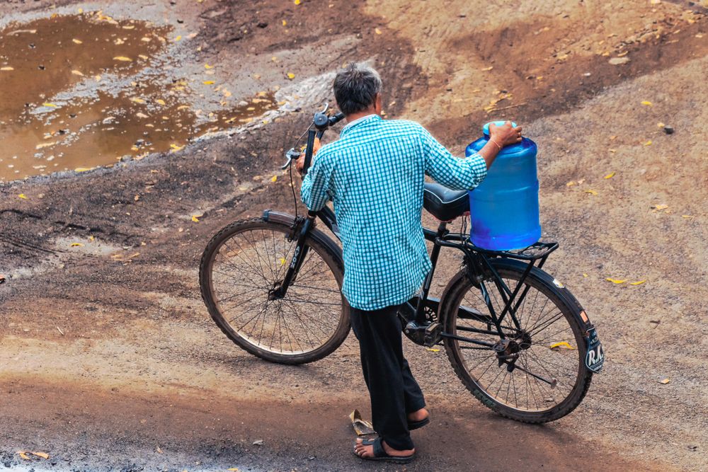 Back view of man walking beside bicycle on dirt road