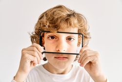 Child posing with his mobile phone and photos made of parts of his face