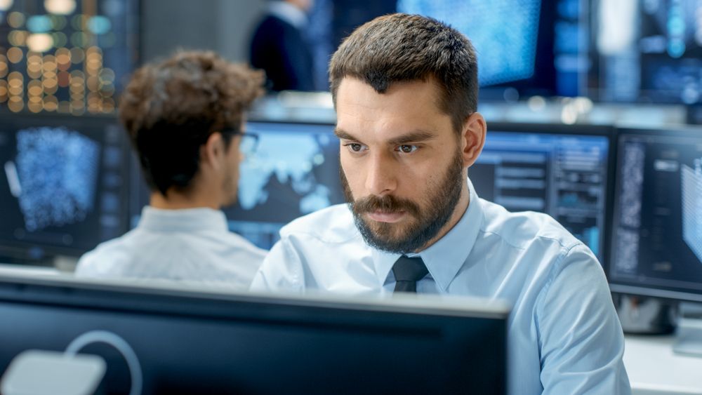 Neural Network and Machine Learning Engineer Programming at His Workstation. Office is Crowded With People Working.