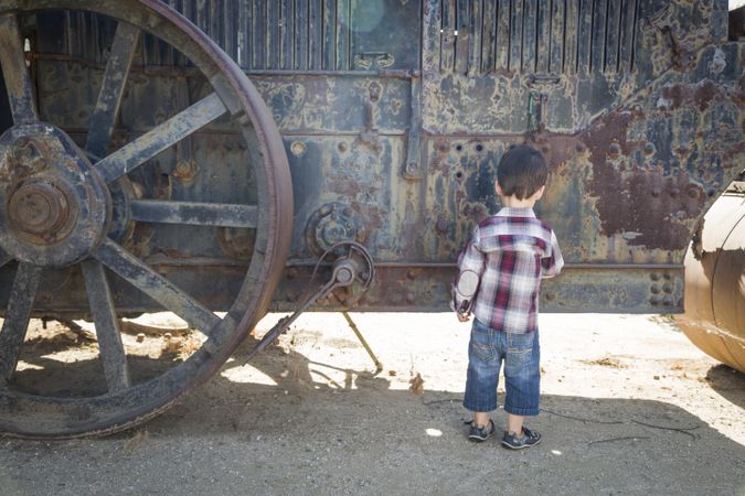 Young Biracial Boy Having Fun Near Antique Machinery